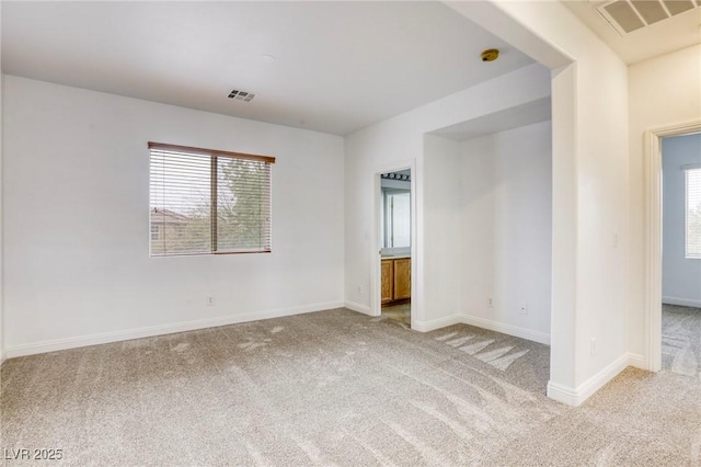 unfurnished room featuring plenty of natural light, light colored carpet, and visible vents