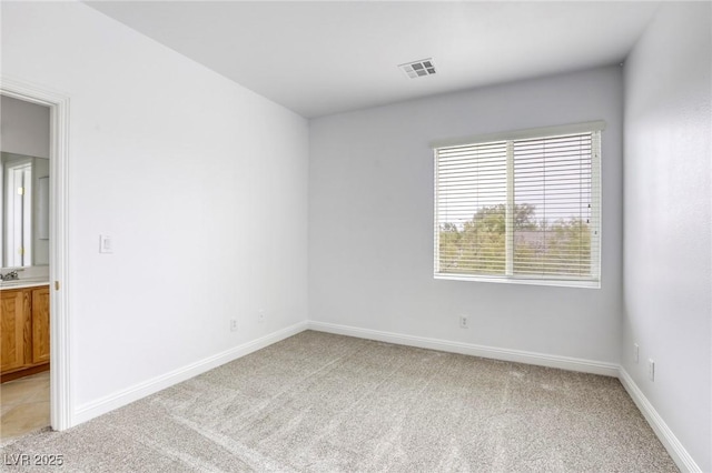 empty room with visible vents, light carpet, and baseboards