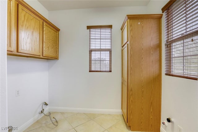 laundry room with light tile patterned floors, cabinet space, and baseboards