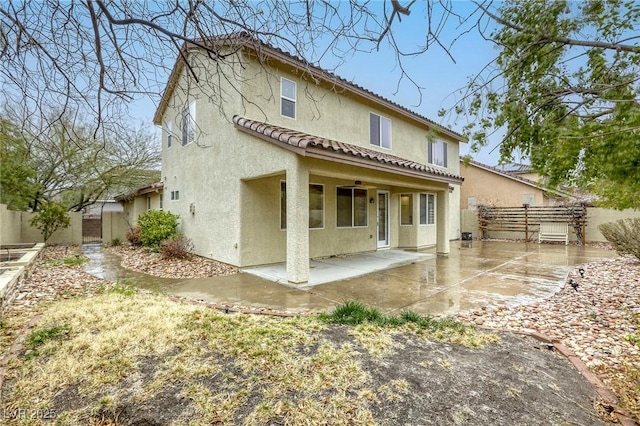 back of property with a tiled roof, a patio area, fence, and stucco siding