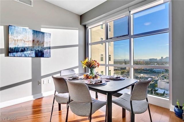 dining room with wood finished floors, visible vents, and a healthy amount of sunlight