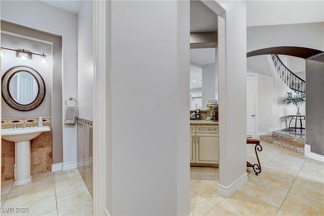 hallway with light tile patterned floors, arched walkways, and stairs