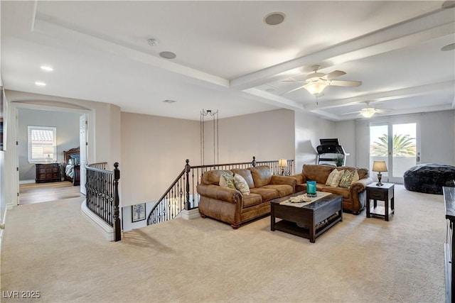 living area with arched walkways, plenty of natural light, light carpet, and beam ceiling