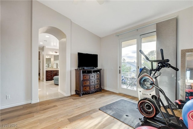 workout area with vaulted ceiling, wood finished floors, arched walkways, and baseboards