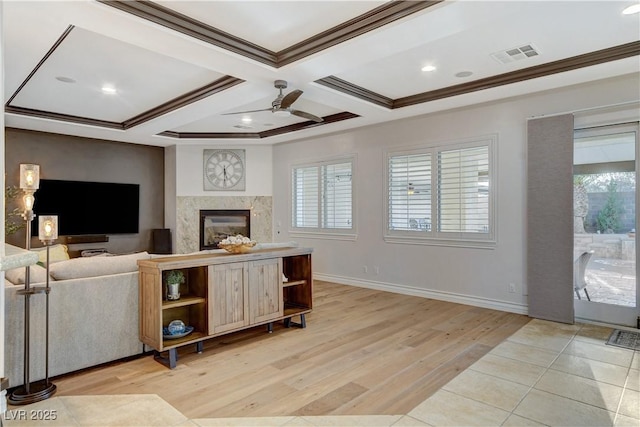 living room featuring visible vents, coffered ceiling, a premium fireplace, light wood-style floors, and crown molding