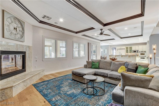 living area featuring visible vents, ornamental molding, wood finished floors, and a premium fireplace