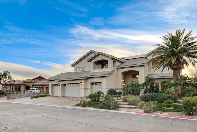 view of front of house featuring an attached garage, driveway, roof mounted solar panels, and stucco siding