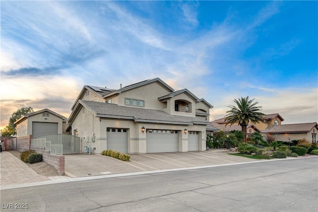 view of front of house featuring solar panels, fence, stucco siding, driveway, and a gate