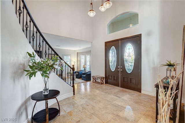 foyer featuring baseboards, a high ceiling, and stairs