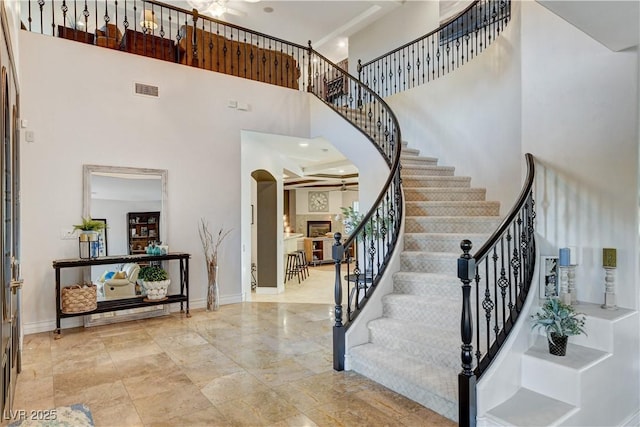 foyer entrance with arched walkways, visible vents, a towering ceiling, and baseboards