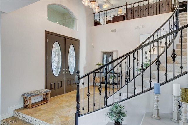 entryway featuring visible vents, a towering ceiling, baseboards, a chandelier, and stairs