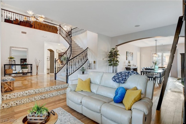 living room featuring stairs, visible vents, wood finished floors, and arched walkways