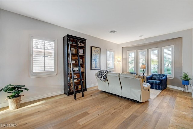 living area featuring visible vents, baseboards, and light wood-style floors