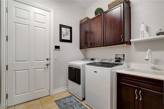 laundry room featuring washing machine and clothes dryer, baseboards, light tile patterned floors, cabinet space, and a sink