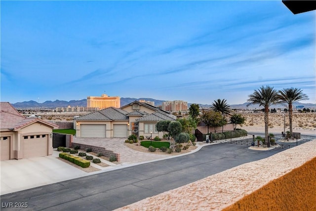 view of front of home with an attached garage, a tiled roof, stucco siding, driveway, and a mountain view