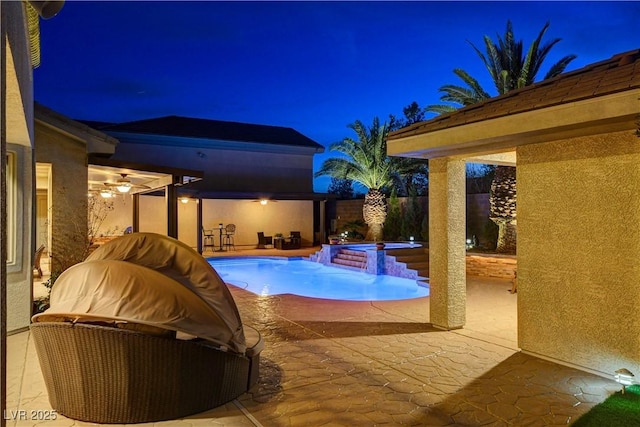 pool at night featuring a pool with connected hot tub, area for grilling, a patio area, and a fenced backyard