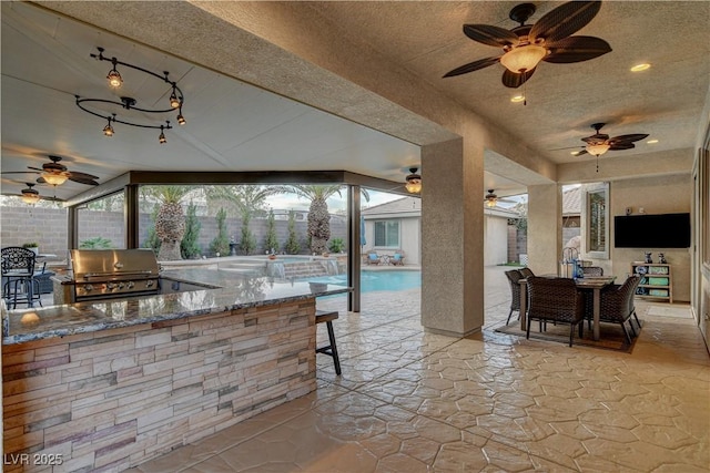 view of patio with outdoor dry bar, fence, outdoor dining space, area for grilling, and an outdoor kitchen