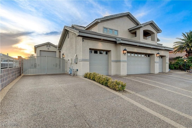 exterior space with a gate, fence, driveway, stucco siding, and a garage