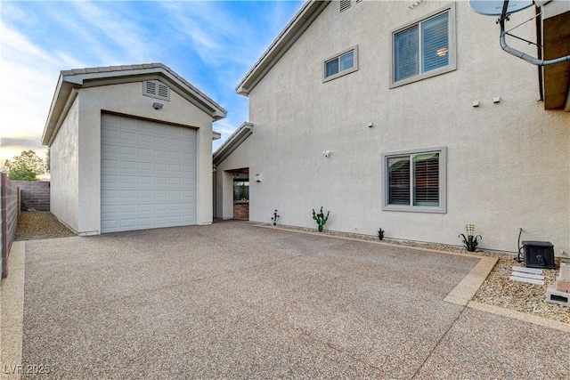 view of home's exterior featuring stucco siding, central AC, an outdoor structure, and fence