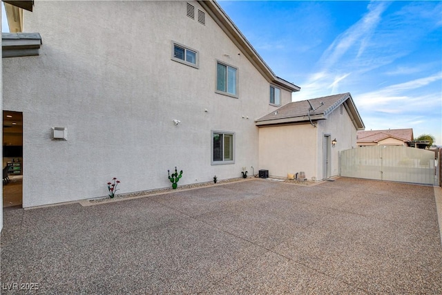 view of property exterior featuring a patio, a gate, and stucco siding