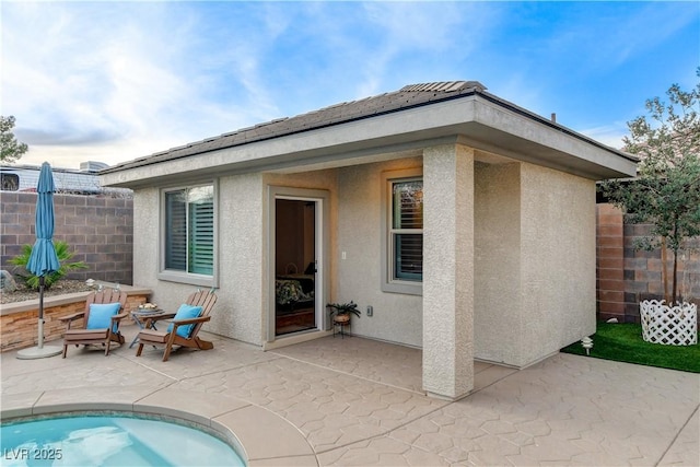 rear view of property with stucco siding and fence