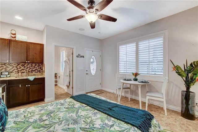 bedroom featuring ceiling fan, ensuite bath, baseboards, and a sink