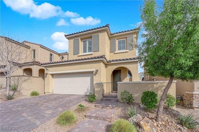 mediterranean / spanish-style home with a fenced front yard, a tile roof, stucco siding, decorative driveway, and a gate