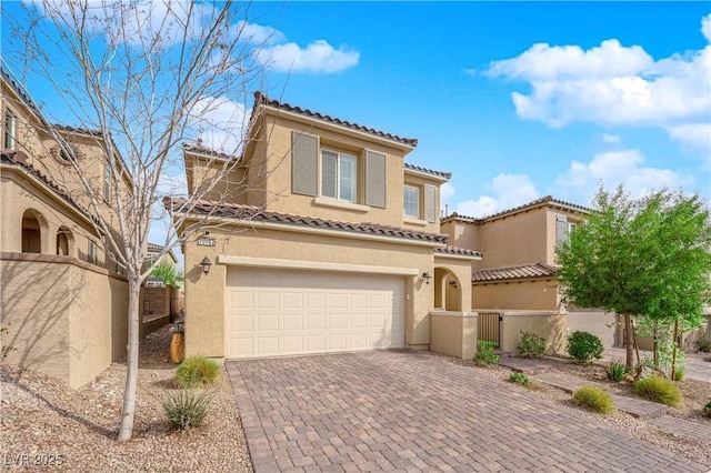 mediterranean / spanish home featuring decorative driveway, fence, a garage, and stucco siding