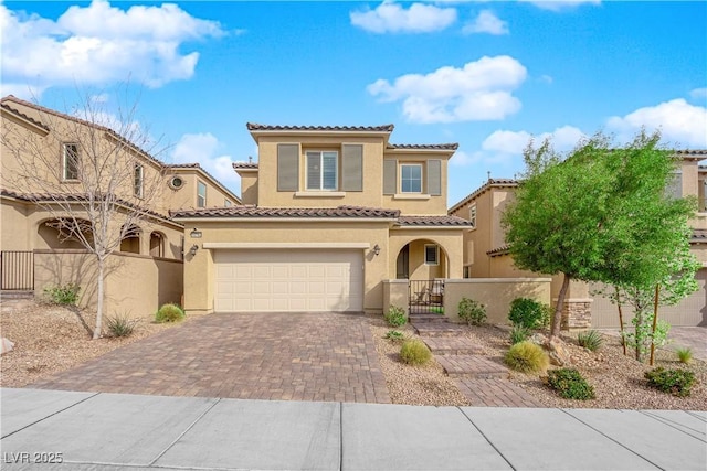 mediterranean / spanish home with a fenced front yard, stucco siding, decorative driveway, an attached garage, and a gate