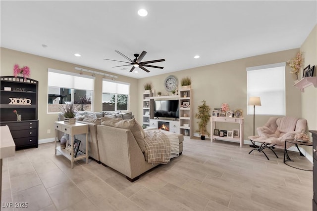 living room with recessed lighting, baseboards, a glass covered fireplace, and a ceiling fan