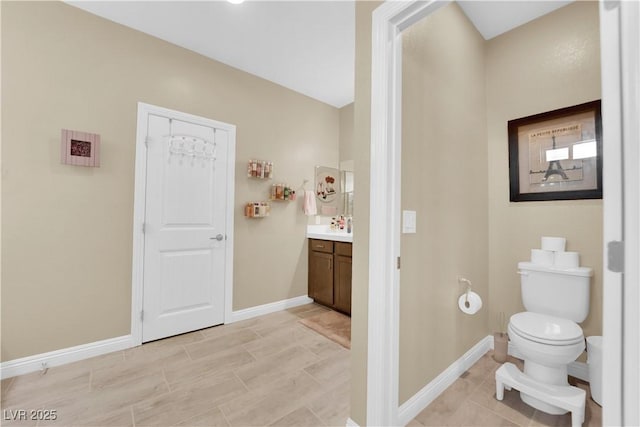 bathroom featuring baseboards, toilet, and vanity