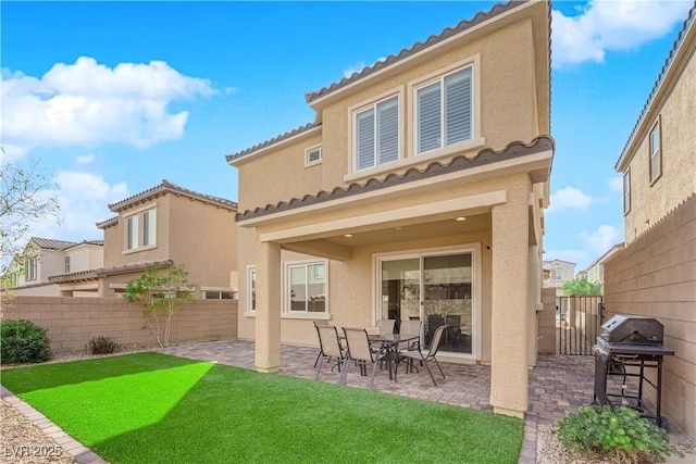 rear view of property with a patio area, stucco siding, a lawn, and fence