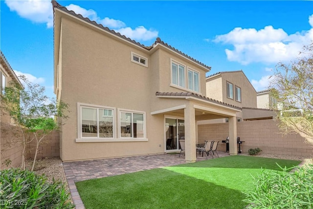 back of house featuring stucco siding, a fenced backyard, a yard, a patio area, and a tiled roof