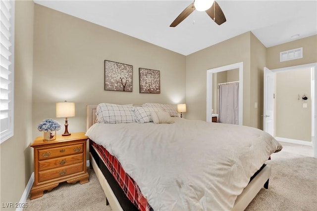 bedroom featuring visible vents, light carpet, baseboards, and ensuite bath