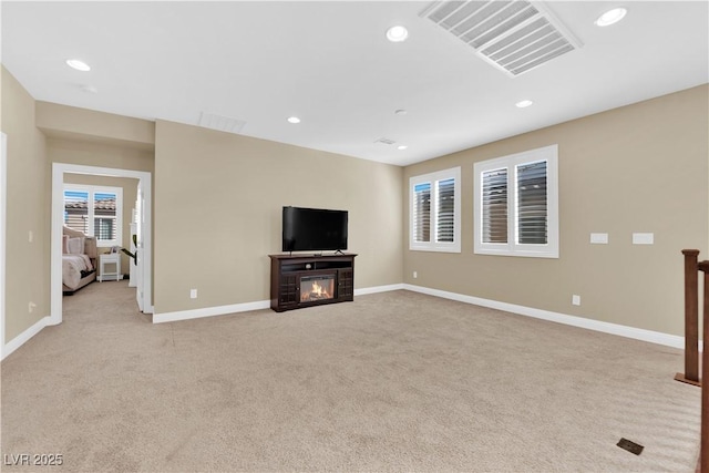 unfurnished living room featuring a glass covered fireplace, recessed lighting, light colored carpet, and visible vents