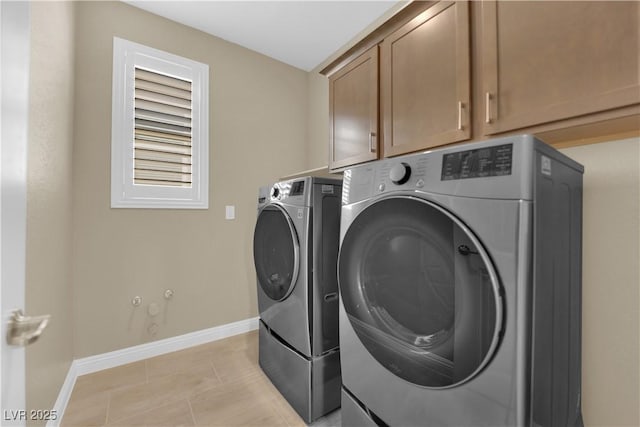 laundry room featuring washer and clothes dryer, light tile patterned floors, cabinet space, and baseboards