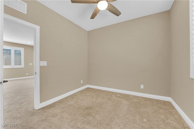 empty room featuring ceiling fan, light colored carpet, visible vents, and baseboards