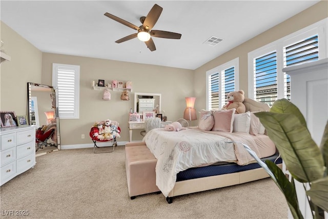 bedroom featuring visible vents, light colored carpet, a ceiling fan, and baseboards