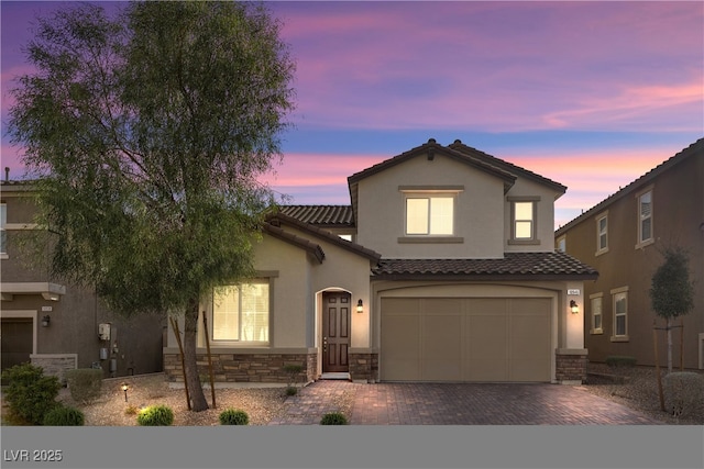 view of front of property with an attached garage, stucco siding, stone siding, a tile roof, and decorative driveway