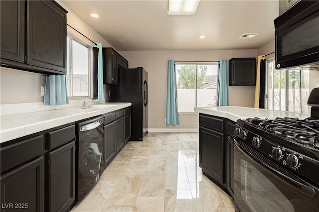 kitchen featuring tile countertops, baseboards, visible vents, a sink, and black appliances