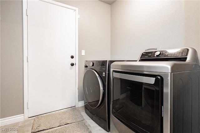 clothes washing area featuring laundry area, washing machine and dryer, and baseboards