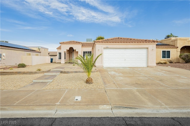 mediterranean / spanish home featuring fence, a tiled roof, concrete driveway, stucco siding, and a garage