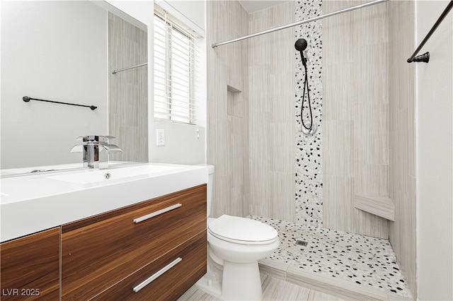 bathroom with vanity, toilet, and a tile shower