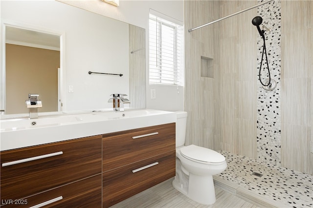 full bathroom featuring toilet, ornamental molding, tiled shower, tile patterned floors, and vanity