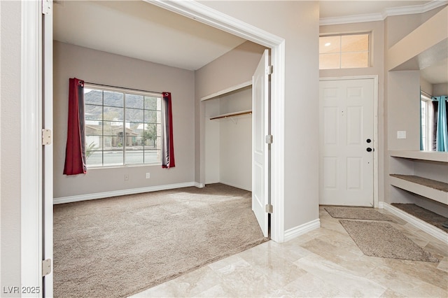 carpeted entryway with baseboards and crown molding