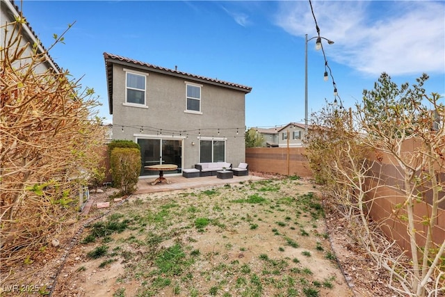 rear view of house featuring stucco siding, a fenced backyard, and a patio area