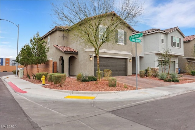 mediterranean / spanish-style house featuring driveway, an attached garage, stucco siding, a tile roof, and a residential view