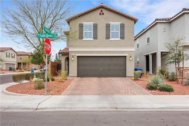 view of front of house with stucco siding, decorative driveway, a garage, and a tiled roof