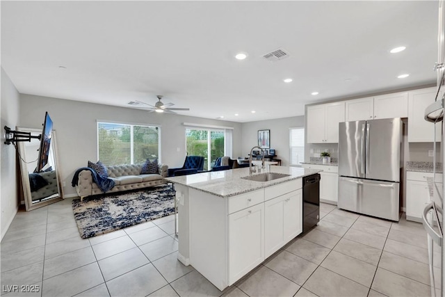 kitchen featuring light tile patterned floors, freestanding refrigerator, black dishwasher, and a sink