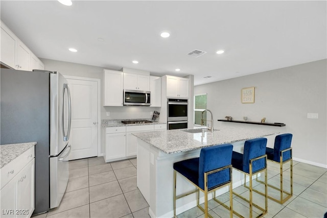 kitchen with visible vents, a breakfast bar, a sink, white cabinetry, and appliances with stainless steel finishes